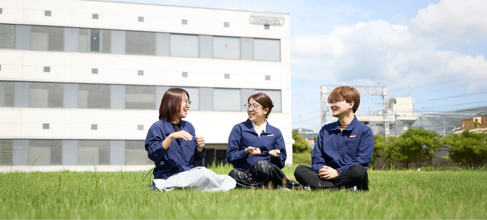Photo of 3 Mario Club employees sitting in front of the current office building