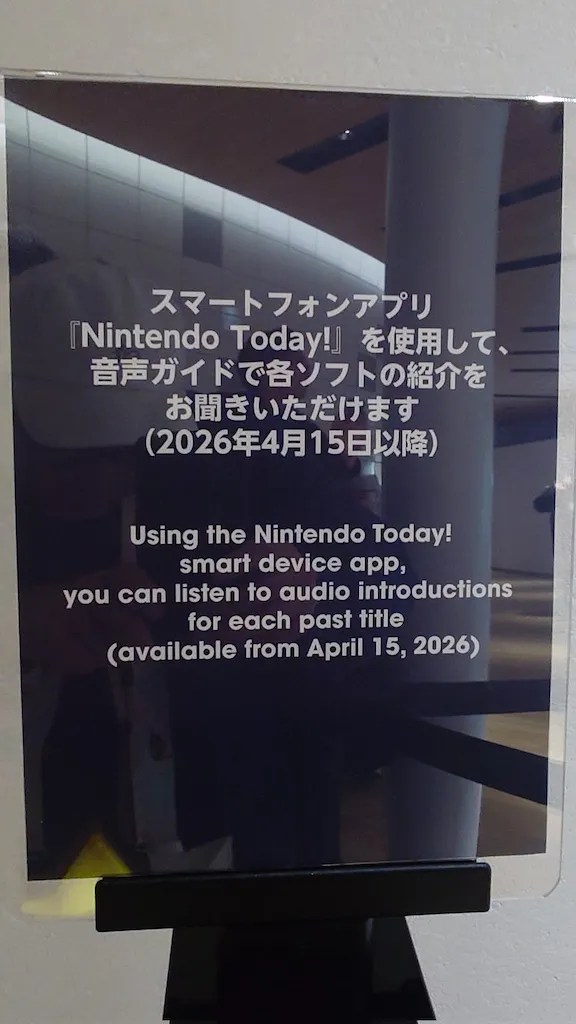 Photo of a placard announcing the interactive guide within the Nintendo Today app: スマートフォンアプリ『Nintendo Today!』を使用して、音声ガイドで各ソフトの紹介をお聞きいただけます(2026年4月15日以降) Using the Nintendo Today! smart device app, you can listen to audio introductions for each past title (available from April 15, 2026)