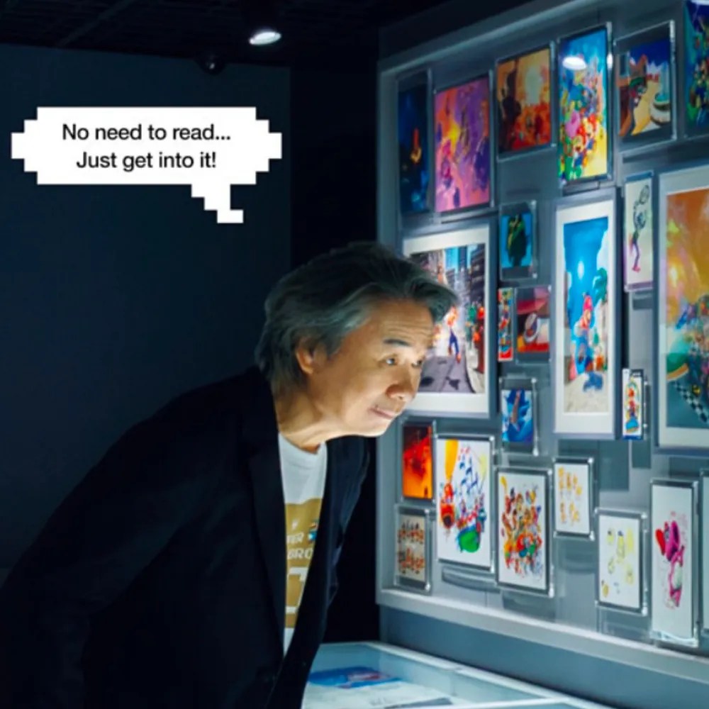 A cropped image from Casa BRUTUS mook: SUPER MARIO BROS. AND DESIGN Shigeru Miyamoto looking at the exhibits in Nintendo Museum, with a thought bubble over his head: “No need to read… Just get into it!”