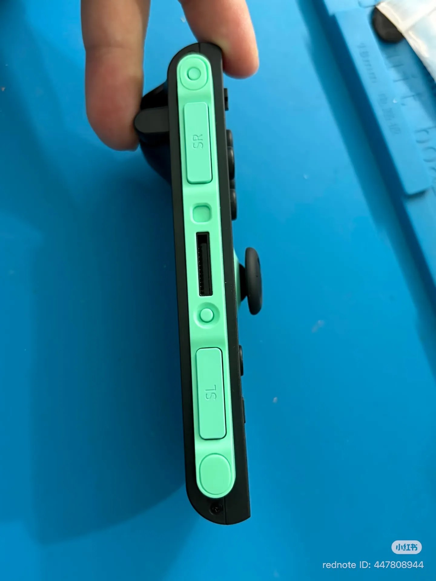 Photo of a counterfeit Joy-Con 2 (right, green), connector side exterior; there is no mouse sensor hole