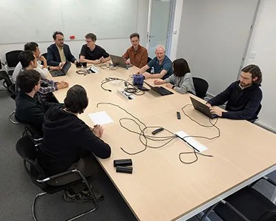 Photo of Nintendo employees having a meeting around a conference table; a GameCube can be seen on the table