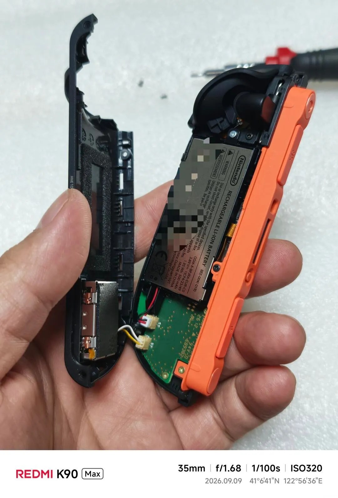Photo of partially disassembled Joy-Con 2 (EU version), with the back shell half-removed