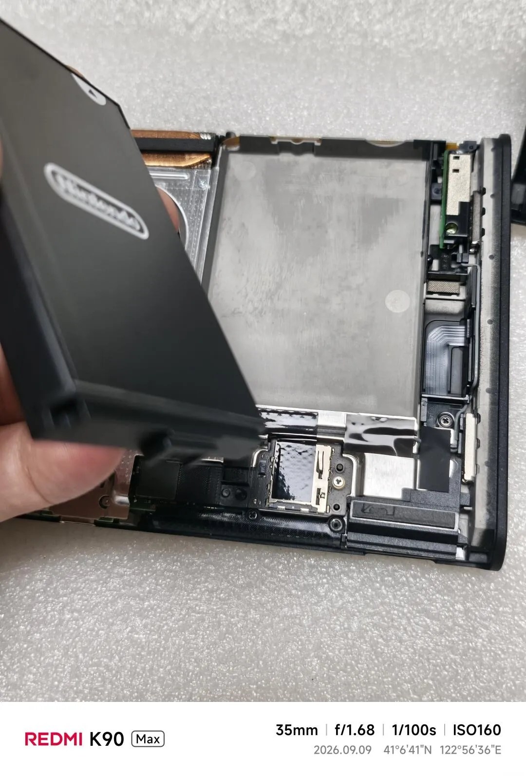 Photo of an EU version of Switch 2 console partially disassembled; the connector on the battery, and the upper right antenna are both visible